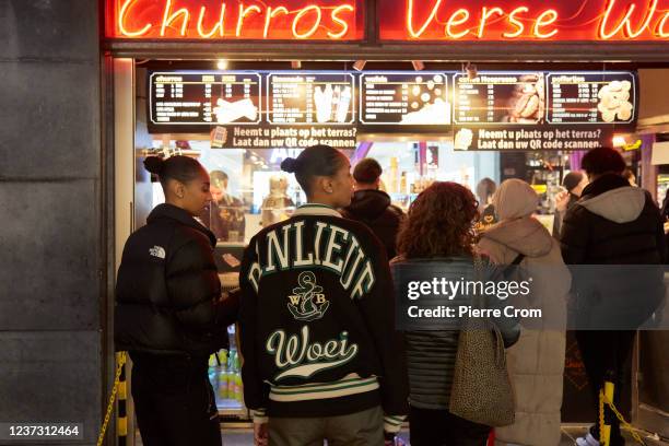 Customers queue for snacks in a shopping street on December 18, 2021 in Rotterdam, Netherlands. The authorities advice not to travel to Rotterdam as...