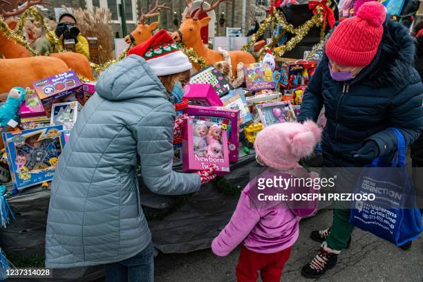 Volunteer offers dolls to a girl and her mom at the Grace Food Pantry in Everett, Massachusetts, on December 18, 2021. - The pantry serves thousands...