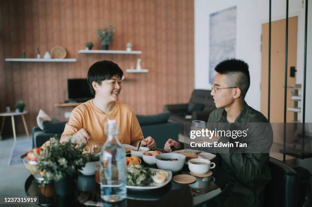 eine asiatische chinesische mutter mit gesundem frühstück mit ihrem teenager-sohn im esszimmer in der morgendlichen bonding-zeit - teenagers eating with mum stock-fotos und bilder