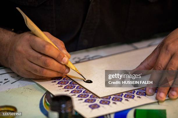 Iraqi calligrapher Wael al-Ramadan uses a stylus to produce a sample of Arabic calligraphy in the "Diwani" calligraphic style at his workship in...