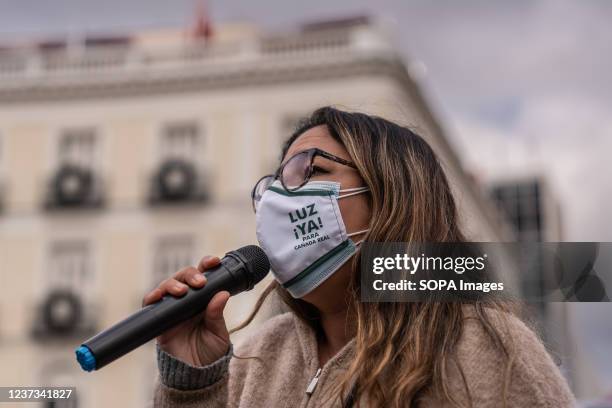 Woman wearing a facemask that reads 'Electricity Now' speaks to protesters during the demonstration. A group of people chanting slogans demonstrate...