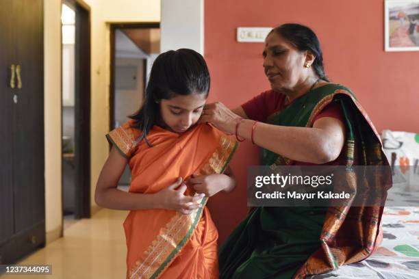 grandmother wearing sari to granddaughter - woman in red sari stock-fotos und bilder