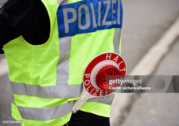 November 2021, Hamburg: A policewoman directs the traffic with a trowel with the inscription "Halt Polizei". Photo: Daniel Bockwoldt/dpa