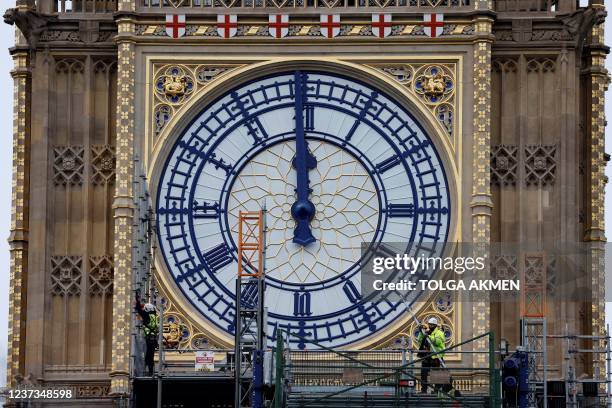 Workers remove the scaffolding from the restored west dial of the clock on Elizabeth Tower, commonly known by the name of the bell Big Ben, at the...