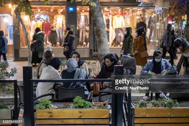 Iranian women sit at an outdoor cafe in the city of Isfahan, 450 km south of Tehran, at night on December 14, 2021. A spokesman for Isfahan...