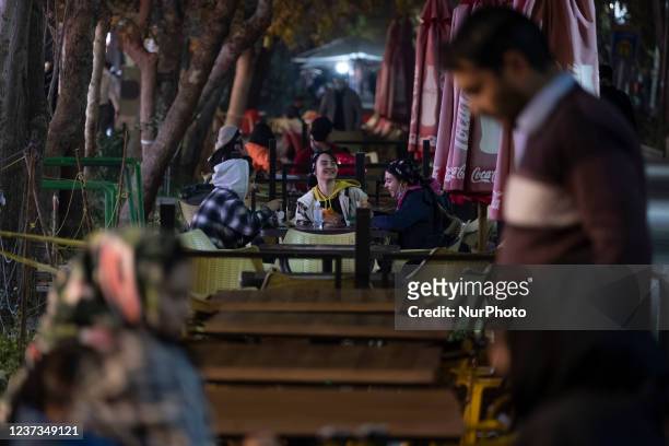 Iranian women talk to each other as they sit at an outdoor cafe in the city of Isfahan, 450 km south of Tehran, at night on December 14, 2021. A...