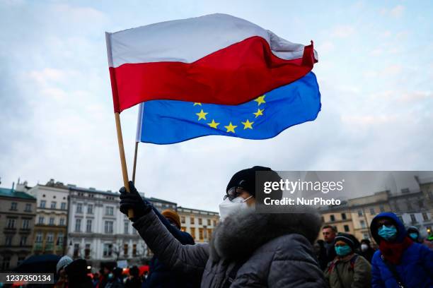 Woman holds Polish and EU flags while attending 'Free People, Free Media' protest at the Main Square in Krakow, Poland on December 19, 2021....