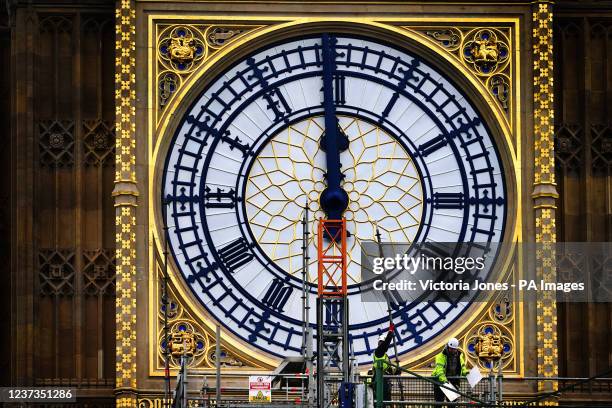 Construction workers remove the scaffolding from the restored west dial of the clock on Elizabeth Tower, known as Big Ben, at the Palace of...