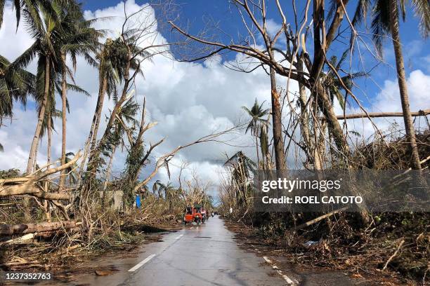Tricycles speeds past fallen coconut trees at the height of Super Typhoon Rai along a highway in Del Carmen town, Siargao island on December 20 days...