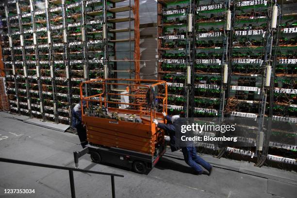 Technicians move a cherry picker to inspect racks of mining rigs at the Minto cryptocurrency mining center in Nadvoitsy, Russia, on Friday, Dec. 17,...