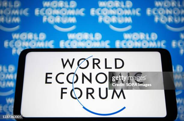 In this photo illustration, the World Economic Forum logo is seen displayed on a smartphone screen and in the background.