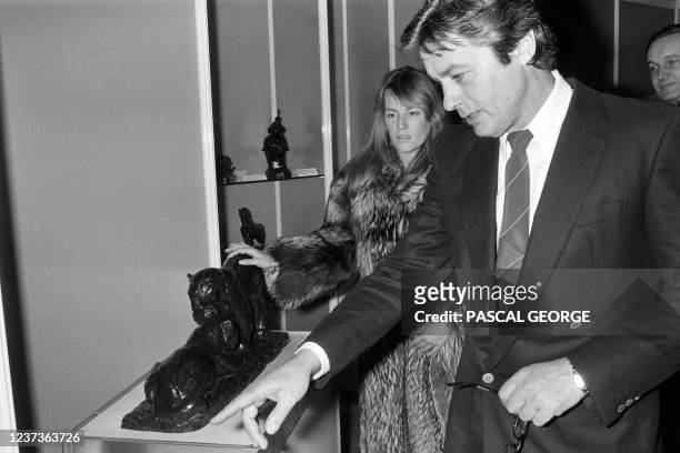 French actor Alain Delon, followed by his partner Catherine Pironi, presents his collection of art works at Drouot Montaigne during the 8th birthday...