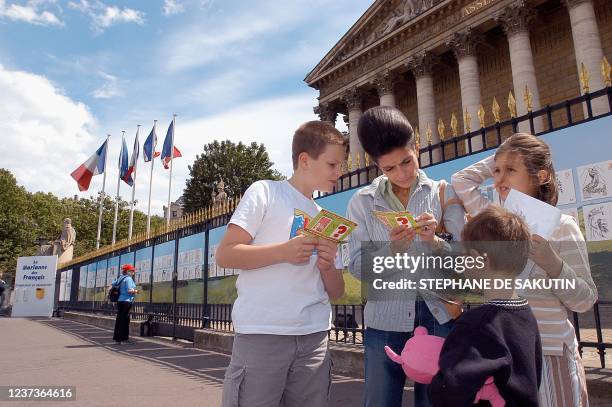 Une famille s'apprête le 20 juin 2004 devant les grilles l'Assemblée nationale à Paris, à choisir parmi 100 dessins de Marianne, les 10 finalistes du...