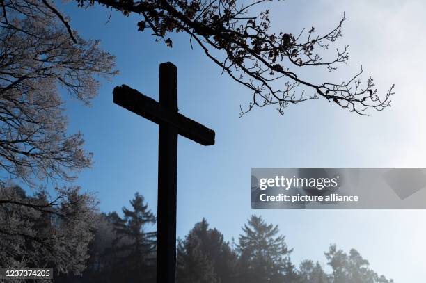 December 2021, Baden-Wuerttemberg, Rottweil: A wooden cross is silhouetted against the morning backlight. Photo: Silas Stein/dpa