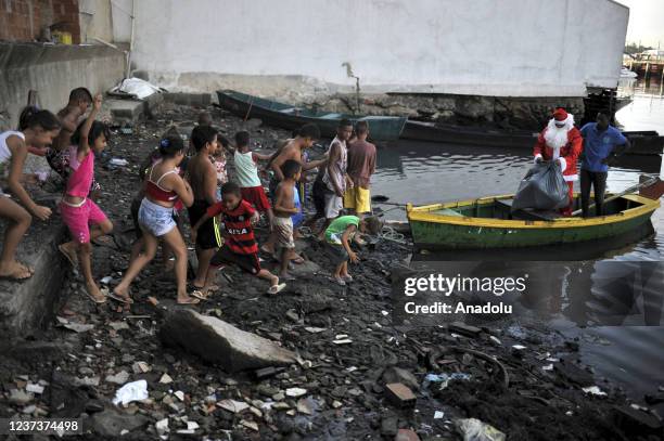 Man in Santa Claus costume distributes sweets and toys for the children in Favela da Mare, in Rio de Janeiro, Brazil on December 19, 2021. Santa...