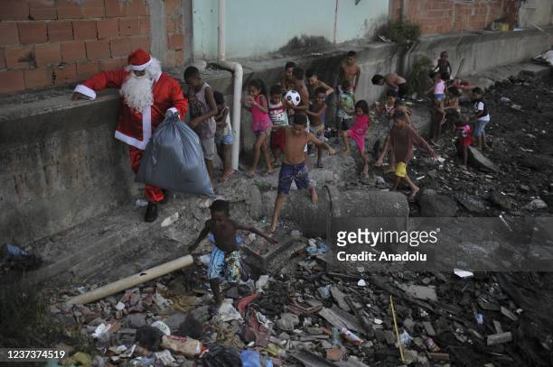 Man in Santa Claus costume distributes sweets and toys for the children in Favela da Mare, in Rio de Janeiro, Brazil on December 19, 2021. Santa...
