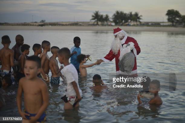 Man in Santa Claus costume distributes sweets and toys for the children in Favela da Mare, in Rio de Janeiro, Brazil on December 19, 2021. Santa...