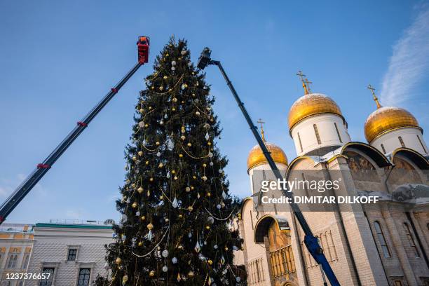 Workers decorate the main Russian 28-metre-high New Year tree at the Kremlin's Sobornaya Square in downtown Moscow on December 22 with the air...
