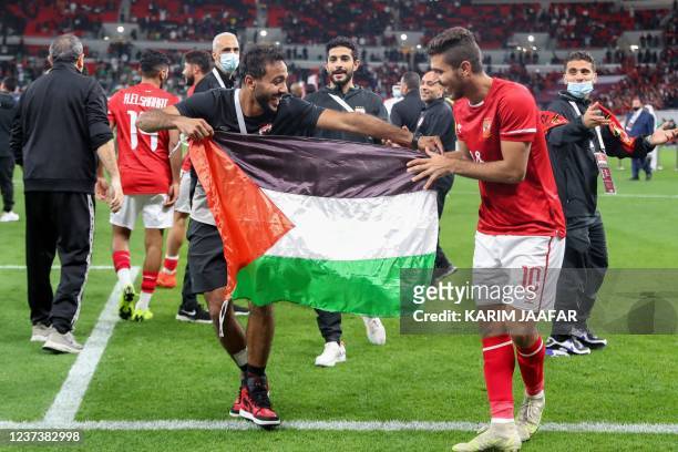 Ahly's players wave a Palestinian national flag after winning the CAF Super Cup football match between Egypt's Al-Ahly and Morocco's Raja Club...