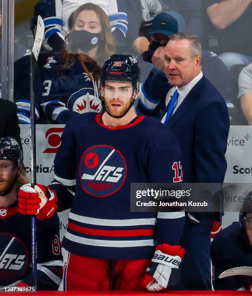 Adam Lowry and his father interim head coach Dave Lowry of the Winnipeg Jets look on from the bench during third period action against the Washington...