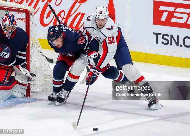 Nate Schmidt of the Winnipeg Jets and Aliaksei Protas of the Washington Capitals battle for puck possession during third period action at Canada Life...