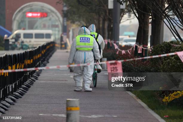 This photo taken on December 22, 2021 shows security guards walking in an area that is under restrictions following a recent coronavirus outbreak in...