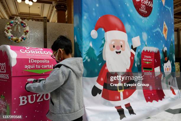 Children hep by their parents write a letter to Santa Claus to deposit it in the Christmas mailbox to receive their gifts in this Christmas season at...