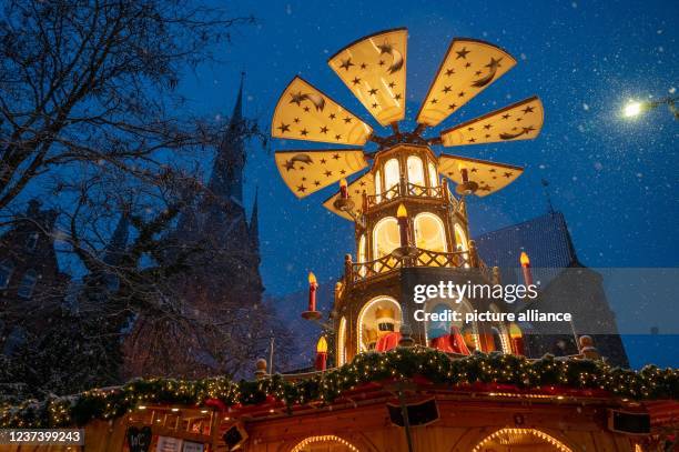December 2021, Schleswig-Holstein, Flensburg: In the evening, when the snow falls, the festively illuminated large Christmas pyramid lights up the...