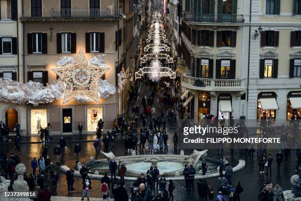 Pedestrians walk in a shopping street of Rome on December 23, 2021.