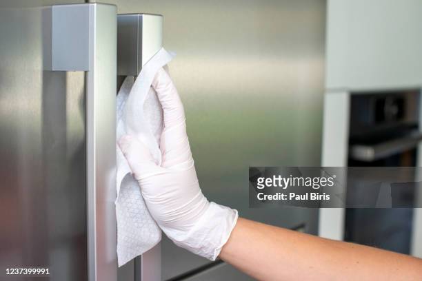 woman cleans refrigerator handle using disinfectant wipe, coronavirus concept, covid-19 - fridge handle stock pictures, royalty-free photos & images