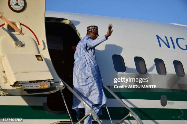 Nigerian President Muhammadu Buhari waves as he gets into the plane after addressing troops at the airforce base in Maiduguri on December 23, 2021. -...