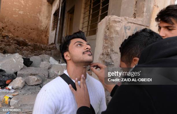 Makeup artists of a film school, prepare an actor before shooting a scene, in the war-ravaged northern Iraqi city of Mosul, on December 15, 2021. -...