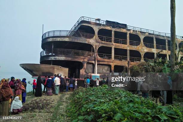 Villagers look at a burnt-out ferry after it caught on fire killing at least 37 people in Jhalkathi, 250 kilometres south of Dhaka, on December 24,...