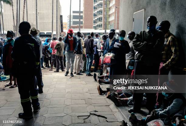 People queue for US dollars at a bank early in the morning, with some having slept in line a day before Christmas, in Harare on December 24, 2021. -...