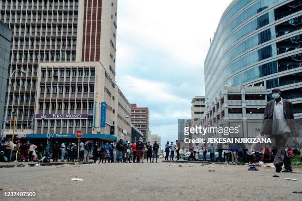 People queue for US dollars at banks early in the morning, with some having slept in line a day before Christmas, in Harare on December 24, 2021. -...