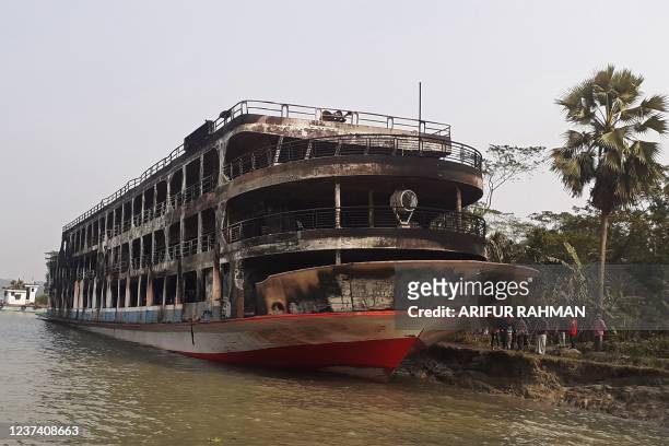 The burnt-out ferry is seen anchored along a coast a day after it caught fire killing at least 37 people in Jhalkathi, 250 km south of Dhaka on...