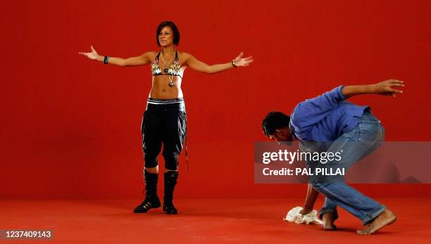 An Indian actress gestures as a support staff member cleans the floor and background in-between the filming of a musical number on a set at Kamlistan...