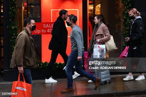 Shoppers, some wearing face coverings to combat the spread of Covid-19, pass High Street stores on Christmas Eve in Guildford, south of London on...