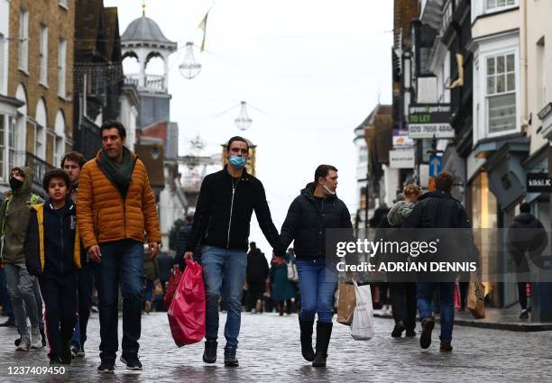 Shoppers, some wearing face coverings to combat the spread of Covid-19, pass High Street stores on Christmas Eve in Guildford, south of London on...