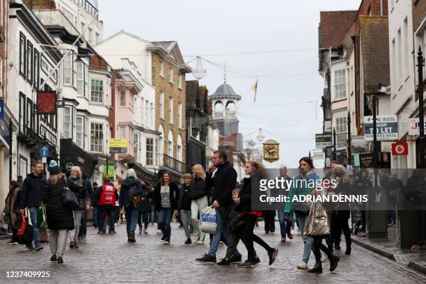 Shoppers, some wearing face coverings to combat the spread of Covid-19, pass High Street stores on Christmas Eve in Guildford, south of London on...
