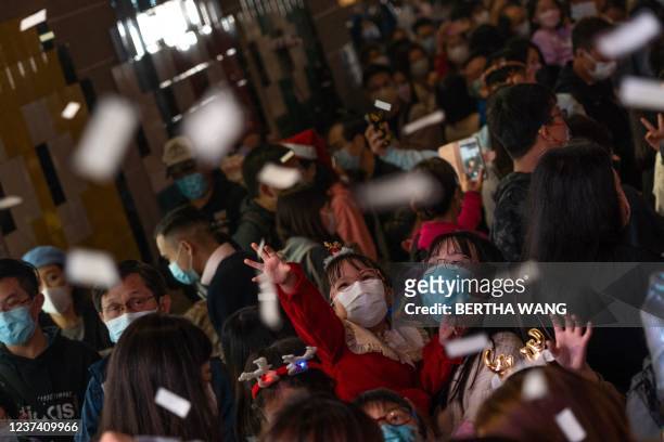 Girl tries to catch the white confetti on the eve of Christmas in Hong Kongs Tsim Sha Tsui area on December 24, 2021.