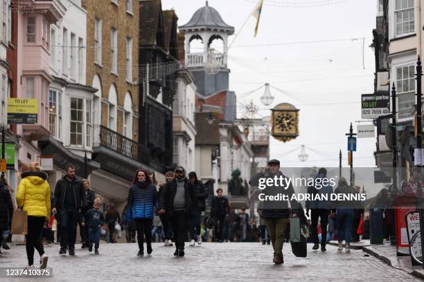 Shoppers, some wearing face coverings to combat the spread of Covid-19, pass High Street stores on Christmas Eve in Guildford, south of London on...