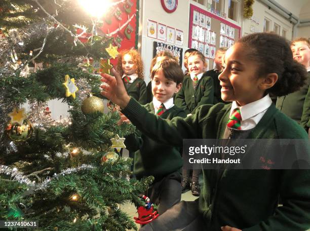 In this handout image released on December 24, children at The Royal School, Windsor, who made 100 white and gold stars to decorate the Christmas...