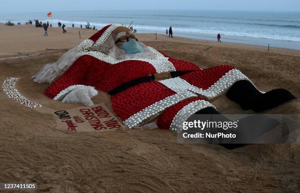 Sand sculpture of Santa Claus is seen on the eastern coast beach of Bay of Bengal at Puri as it is creating by sand artist Sudarshan Pattnaik with...