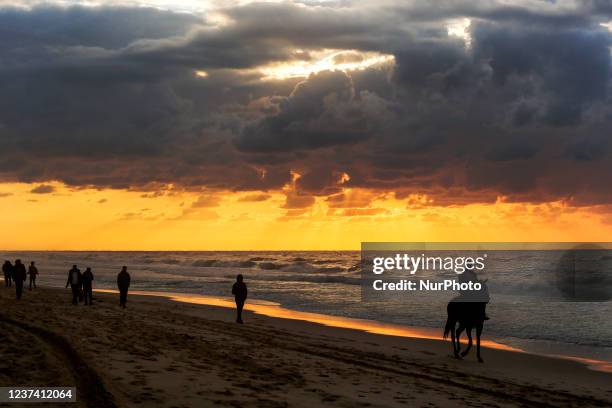 Palestinians enjoy at Gaza beach after heavy rain during sunset, on December 24,2021.