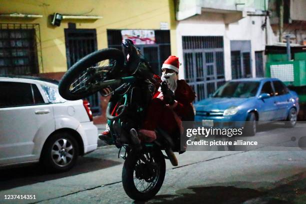 December 2021, Venezuela, Caracas: Motorcyclist Pedro Aldana, widely known in the world of street stunts as "Pedro Locura", dressed as Santa Claus,...
