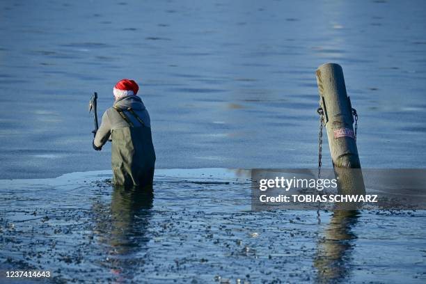 Member of the Berliner Seehunde swimming club breaks the ice wit an axt to take their traditional Christmas bath at the Orankesee lake on December...