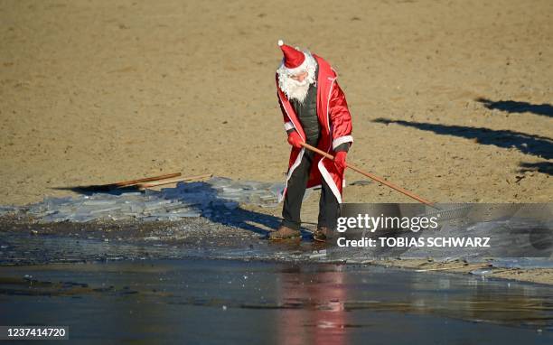 Members of the Berliner Seehunde swimming club dressed as Santa Claus clears the ice to take the traditional Christmas bath at the Orankesee lake on...