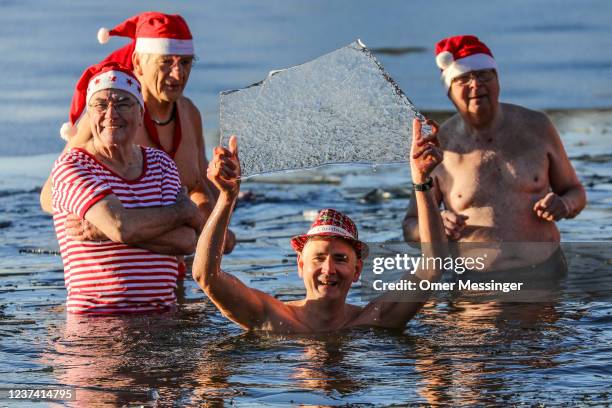 Member of the Berliner Seehunde ice swimming club holds a flat ice piece during a festive dip on Christmas Day at Orankesee lake on December 25, 2021...