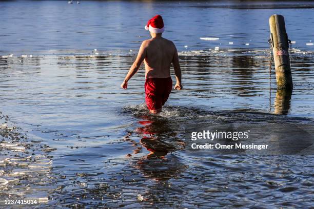 Members of the Berliner Seehunde ice swimming club go for a festive dip on Christmas Day at Orankesee lake on December 25, 2021 in Berlin, Germany....